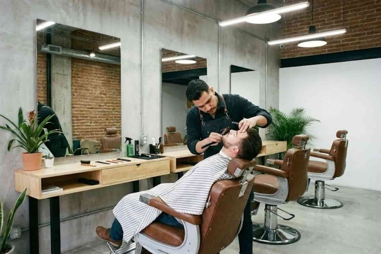 Primer plano de barbero experto realizando un perfilado de contornos con navaja libre en Tlalnepantla de Baz.